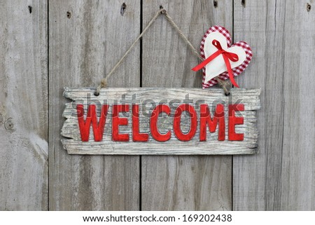 Red wood welcome sign with gingham and muslin heart hanging on wood background