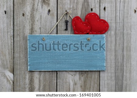 Antique blank blue sign with red hearts and iron key hanging on wood background