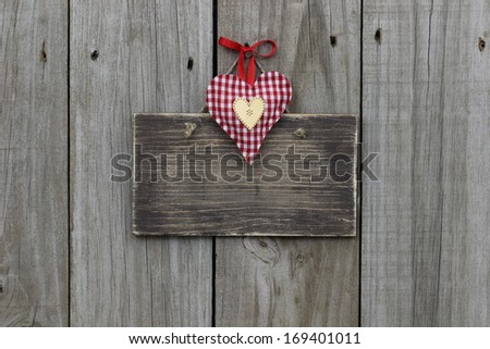Blank wood sign with red checkered (gingham) heart hanging on wood background
