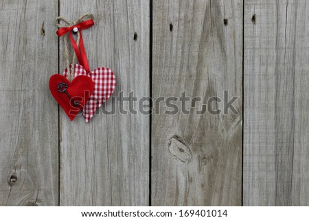 Red heart with iron key and red checkered (gingham) hearts hanging on wood background