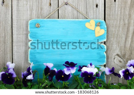 Blank antique blue sign with purple flowers (pansies) hanging on wood background