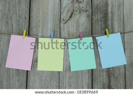 Pastel colored note cards hanging on clothesline with wooden background