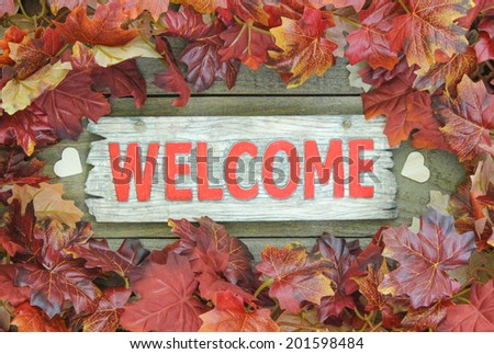 Fall leaves border red wooden welcome sign with wood hearts
