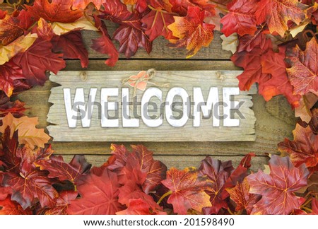 Colorful fall leaves border weathered welcome sign