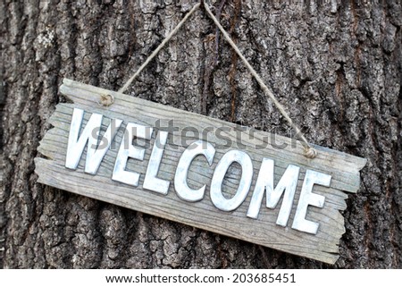 Wood welcome sign hanging on tree