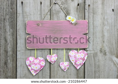 Blank pink weathered sign with daisy hearts hanging on rustic wooden background