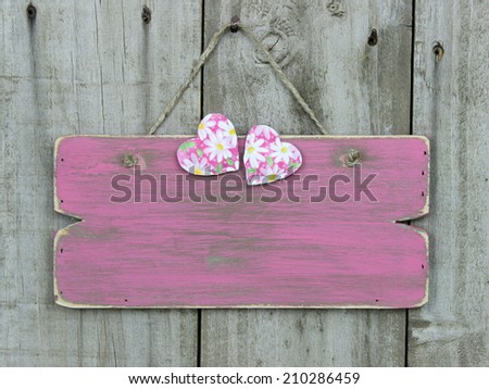 Blank rustic pink sign with daisy hearts hanging on wooden fence