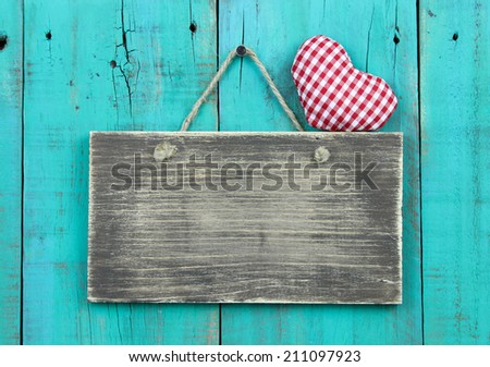 Blank old sign with red checkered heart hanging on weathered antique blue background