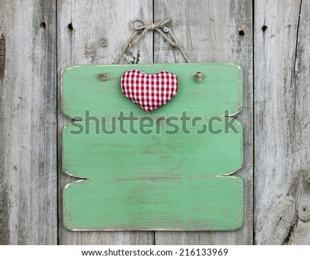 Blank green rustic wood sign with red heart hanging on wooden background