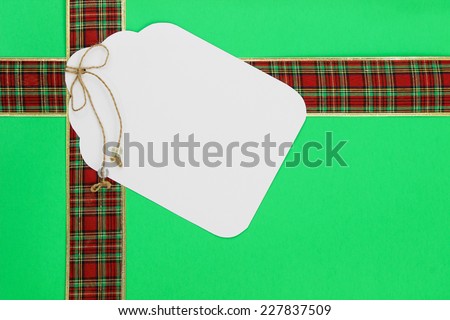 Large gift tag on green Christmas background with red plaid ribbon border