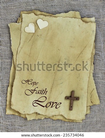 Antique parchment paper letters with HOPE, FAITH, LOVE text and wooden cross and hearts on rugged texture background