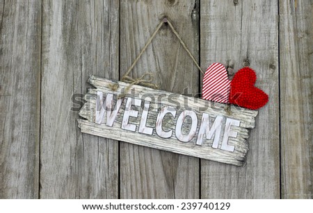 Wood welcome sign with red heart and candy cane striped heart hanging on shabby antique wooden background
