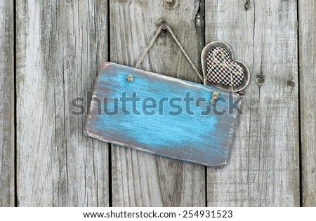 Blank ice teal blue wood sign with country fabric heart hanging on rustic wooden background