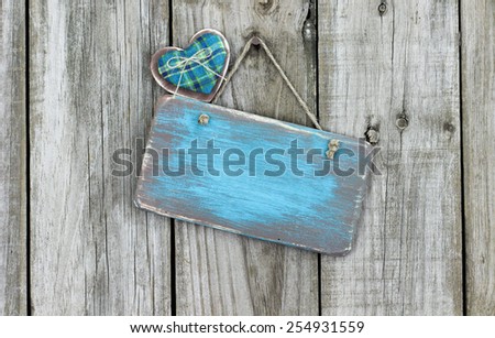 Blank teal blue antique wood sign with country fabric heart hanging on rustic wooden background