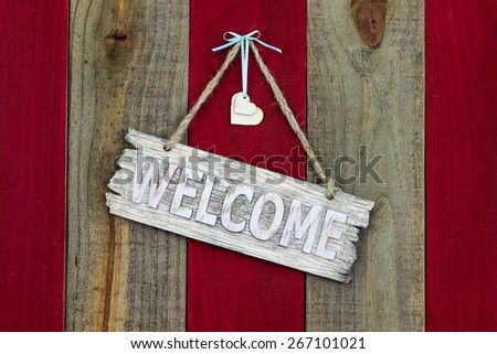 Wood welcome sign with hearts and teal blue ribbon hanging on antique red and wooden rustic background