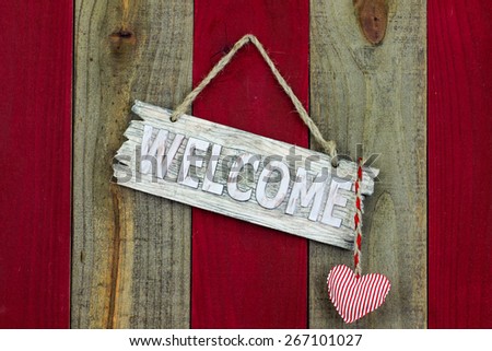 Wood welcome sign with red and white candy cane striped heart hanging on antique red and wooden rustic background