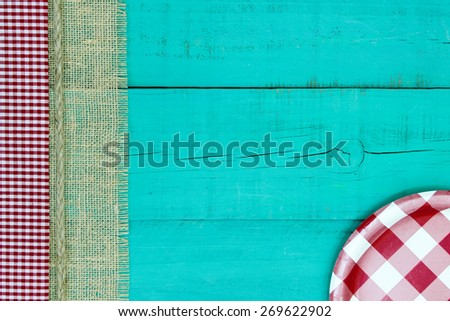 Red and white checkered plate on antique teal blue wood sign with gingham, rope and burlap border; above view looking down