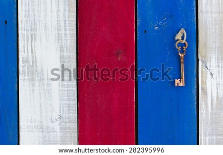 Bronze skeleton key hanging from rope on red, white and blue rustic wooden background