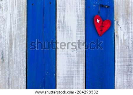 Red broken wood heart  hanging on white and blue rustic wooden background