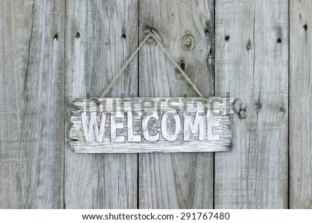 Rustic wood welcome sign hanging on old weathered wooden fence