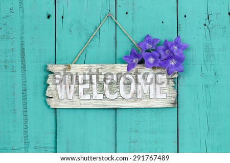 Rustic welcome sign with purple balloon flowers hanging on antique teal blue wooden background