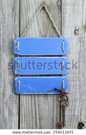 Blank antique blue rustic sign with bronze skeleton key hanging on old wooden background