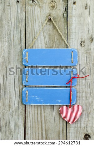 Blank antique blue rustic sign with red and white candy cane striped heart hanging on old wooden background