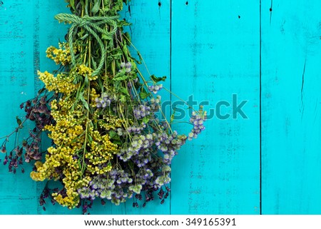 Bouquet of dried meadow flowers hanging by rope on antique rustic teal blue wooden background