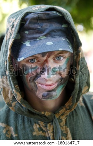 Young soldier face with jungle camouflage, special forces outdoors