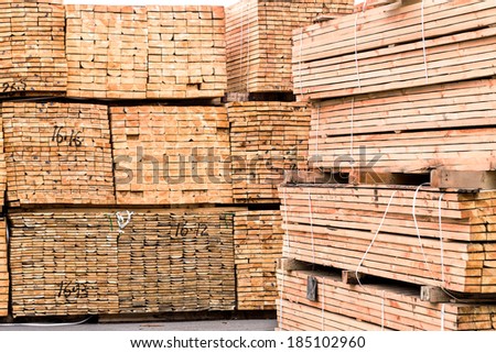 A pile of wood edged boards packed in stacks with tags size parameters for loading cranes and transport the cargo ships in the seaport