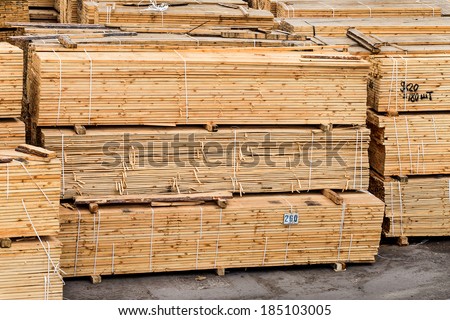 A pile of wood edged boards packed in stacks with tags size parameters for loading cranes and transport the cargo ships in the seaport and railway wagons