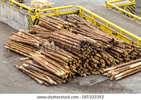 The packaging material. Pile of wooden planks round round-wood used as gasket for metal packaging for loading cranes and transport the cargo ships in the seaport and railway wagons