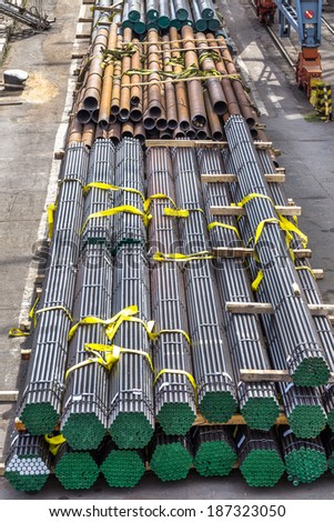 A pile of round and square metal pipes, chocks , packed in stacks with tags size parameters for cranes and transport of cargo ships in the seaport and railway wagons