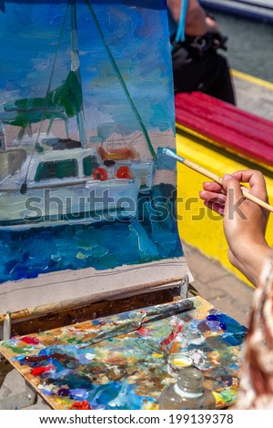 Artist draws a brush and oil paints bright seascape with yachts in the yacht club sea trading port of Odessa