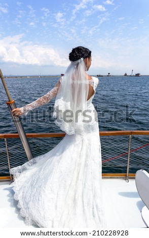 Beautiful bride in a wedding dress walking on sea yacht. The bride in marriage. Woman in wedding dress near the sea. Bride on their wedding day. The girl in a wedding dress on nature. happy wedding.
