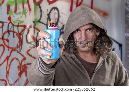 Graffiti artist in a gray dress with hood spray paint for picture on the wall of urban culture. Beautiful street art graffiti. Urban Contemporary Culture. Isolated on white background. selective Focus