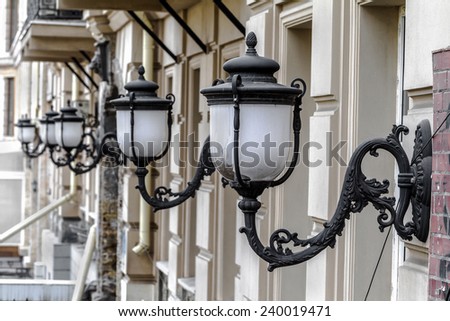 Vintage bronze white street lights in a row on the wall of the house in the afternoon