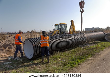 Odessa, Ukraine - December 3, 2013: Sewage pumping station. Stacking round plastic pipe diameter large building special equipment during repair sewer system in Odessa, Ukraine 3 December 2013.