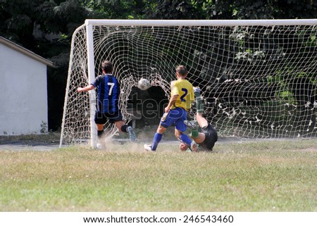 ODESSA, UKRAINE - 14 August 2010: Children play soccer on the school football field. Acute game time - Soccer player scores a goal with a torn mesh