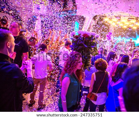 Odessa, Ukraine - May 31, 2014: Large crowd of people having fun in a nightclub at a concert during the creative light and music show. Cheerful young people showered great candy on club party.