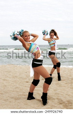 Odessa, Ukraine - September 4, 2010: Bright dynamic performance of women\'s support group sports team on the sandy shores of Black Sea. Cheerleaders in Aktion. Bright beautiful young girl in sportswear