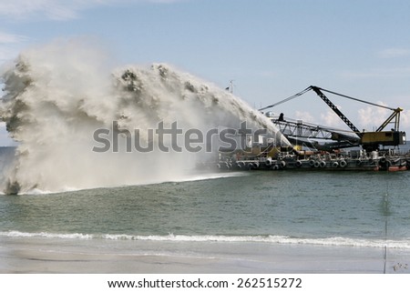 Dredging , panning sand on the beach during the construction of a new sea freight terminal in the harbor of Port