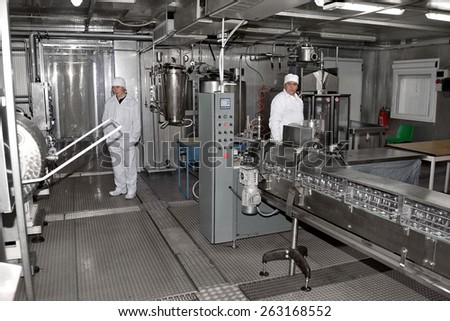 Odessa, Ukraine, April 14, 2011: Modern food processing plant produces milk. Conveyor line with bottles and cans. Workers control workflow