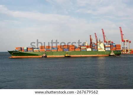 Odessa, Ukraine - 25 august 2008: Large marine ship leaves the container terminal. Powerful marine pilot tug boat from the output port of the bay to the open sea. Sea transportation of cargo