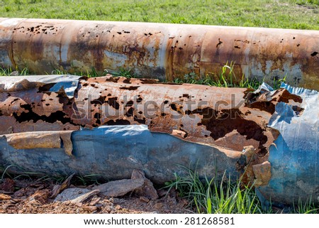 Fragments of old large water pipes. After many years of operation, corroded metal pipe destroyed. Rusty steel tube with holes metal corrosion. Selective focus.