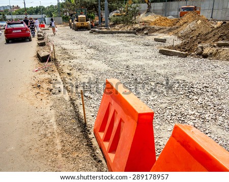 Odessa, Ukraine, June 21, 2015 - Construction of the road. In the dug trench poured layer of stone as a pillow for asphalt. It works construction equipment. Nearby are people.