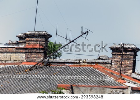 The roof of the old building. Old damaged chimneys of brick and broken television antenna. Creative background for retro design. Background destruction.
