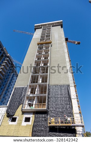 Odessa, Ukraine - October 16, 2015: Work on insulation of facades high-rise apartment building. Warming houses, house wall insulation, waterproofing the walls of house. Modern construction technology