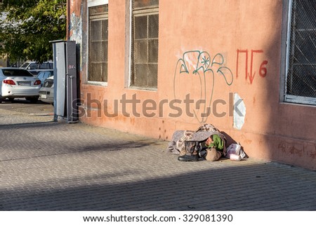Odessa, Ukraine -17 October 2015: Homeless man curled up sleeping on the street. Passing by people who do not pay attention. Ukraine is rapidly becoming the most poor, impoverished country in Europe