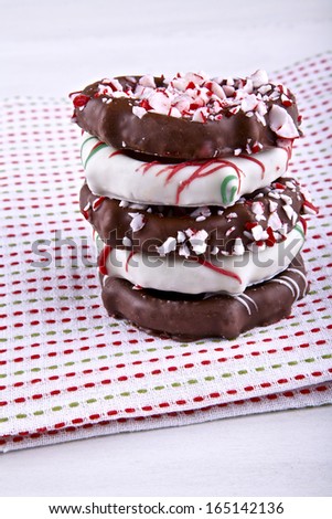 Hard pretzels covered chocolate , topped with decorative holiday flair on lien napkin background